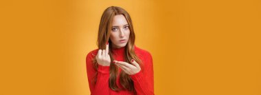 Redhead girl asking where wedding ring being fed up waiting proposal extending finger and pointing at it questioned and pissed having argument with boyfriend over orange background. Relationship and