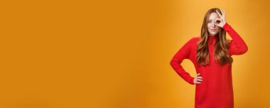 Nişan aldım. Kendine güveni tam, kendine güveni tam, kızıl saçlı, kırmızı elbiseli çekici bir kadın. Ya da gözlerinde hiç işaret yok. Turuncu duvarın üzerinden gülümsüyor gibi görünüyor..