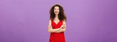 Şirin, hırslı ve mutlu Avrupalı bir kadın. Gösterişli kırmızı elbisesiyle kendinden emin bir şekilde el ele tutuşarak mezuniyeti mor arka planda kutlarken gülümsüyor..