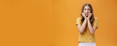 Yaşam tarzı. Panikleyen, aptal, kendine güveni olmayan, korkudan titreyen, tırnaklarını yiyen, parmaklarını ağzında tutan, turuncu arka plandan korkan genç bir kadının portresi..