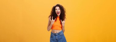 Harika dans eden ve eğlenen bir kadın. Şaşkınlıktan yüksek sesle bağırmak ve heyecan verici rock-n-roll hareketlerini göstermek ağzını açmak ve turuncu arka planda şık bir şekilde poz vermek..