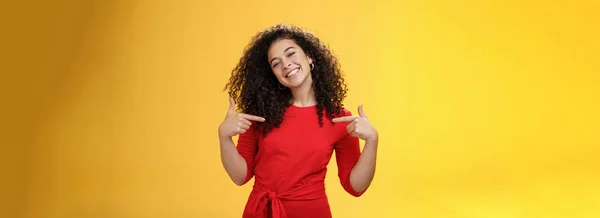 stock image Lifestyle. Proud and satisfied ambitious successful female student in red dress standing pleased smiling and pointing at herself as if bragging about own achievements happily and glad over yellow wall