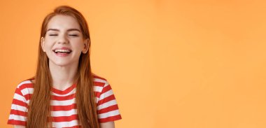 Samimi, mutlu, karizmatik, gülümseyen, kapalı gözlü, yaz güneşinin tadını çıkaran neşeli, rahatlamış hisseden, beyaz dişlerini gösteren, iyi tatil kavramı, turuncu arka plan.