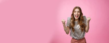 Mutlu, çekici, çekici, genç bir kız zaferi kutluyor. Başarı başarısını haykırıyor, mutluluk çığlıkları atıyor. Yumruklarını sallıyor, zafer jestleri yapıyor, hayallerini gerçekleştiriyor..