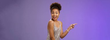 Etkileyici, zarif, afrikalı bir kız. Parlak, gece elbisesi parıldıyor. İşaret parmağı sola dönüyor..