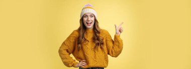 Şaşırtıcı derecede mutlu, neşeli, neşeli genç bir kadın şaşırmış, geniş gözlü, sol üst köşeyi işaret eden komik bir şaka görüyor, heyecanlı arkadaşlar hakkında konuşuyor, yeni alışveriş merkezi, sarı arka plan..