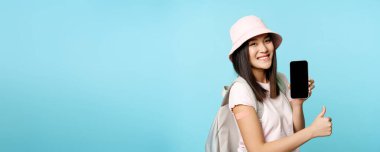 Gülümseyen Asyalı turist kolunda kovid 19 aşısından kalma yama olduğunu gösteriyor. Akıllı telefon uygulamasında koronavirüs aşısı uluslararası sertifikası gösteriyor..