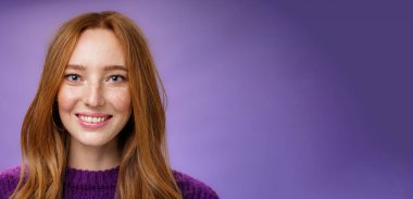 Çekici, çekici ve mutlu kızıl saçlı, çilli, parlak beyaz gülüşlü, mor arka planda poz veren, mutlu ve mutlu bir kadının portresi..