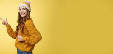 Yaşam tarzı. Profil çekimi karizmatik flört güzel görünümlü genç kız kamerayı sola çevir işaret parmağı göster baş parmaklarını göster jest gibi harika bir yeri tavsiye eden sarı arka plan.