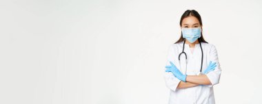 Profesyonel doktor görüntüsü, Asyalı doktor yüzü maskeli, lastik eldiven, kolları çapraz duran, beyaz arka plan..