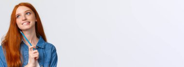 Sevimli ve yaratıcı, düşünceli, hayalperest, gülümseyen, kızıl saçlı kadın güzel bir şey hayal ediyor, elinde renkli bir kalem, çizim, sanat derslerine katılıyor, beyaz arka plan..