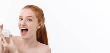 Yüzüne krem sürerken gülümseyen güzel bir kadının portresi. Fotokopi alanı ile izole edilmiş.