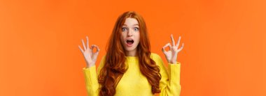 Şaşırmış ve etkilenmiş kırmızı saçlı mavi gözlü, kıvırcık saçlı kadın, çiller harika jestleri olan, ağzı açık, şaşkınlıktan ağzı açık, kameraya bakan, büyüleyici filmi onaylayan..