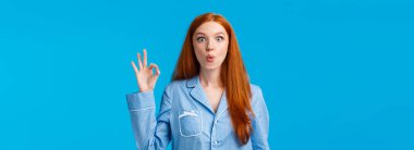 Harika yeni ürünü duyan harika bir kız. Gece elbiseli, şaşkın ve şaşkın kızıl saçlı kadın, kıvrılmış dudaklar, 