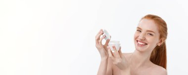 Yüzüne krem sürerken gülümseyen güzel bir kadının portresi. Fotokopi alanı ile izole edilmiş.