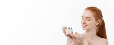 Yüzüne krem sürerken gülümseyen güzel bir kadının portresi. Fotokopi alanı ile izole edilmiş.