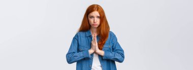 Belden yukarı portre, kasvetli tatlı kızıl saçlı yalvaran kız, dua etmek için el ele tutuşun, kameraya bakın yalvarın, yardım isteyin, özür dilerim, pisliğe sebep olduğum için pişmanlık duyun, beyaz arka plan.