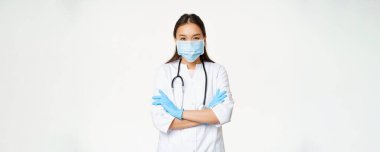 Profesyonel doktor görüntüsü, Asyalı doktor yüzü maskeli, lastik eldiven, kolları çapraz duran, beyaz arka plan..