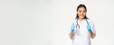 Gülümseyen Asyalı doktor, tıp üniformalı kadın ve lastik eldiven, hastaya 
