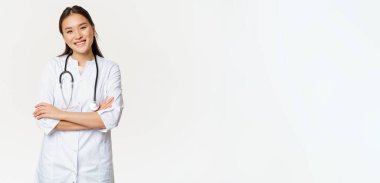 Asyalı kadın doktor, steteskoplu doktor, göğsünde çapraz kollar, gülümsüyor ve profesyonel, beyaz bir geçmiş gibi görünüyor..