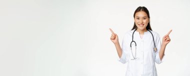 Beyaz cüppeli, gülümseyen profesyonel doktor, parmaklarını yana doğru gösteriyor ve her iki yönde de beyaz arka plana karşı duran iki reklam gösteriyor..