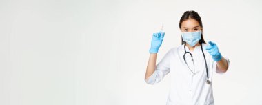 Coronavirus aşısı. Asyalı hekim, elinde aşı şırıngası tutan doktor ve kameralı hastayı işaret eden aşı kampanyası, beyaz arka plan..
