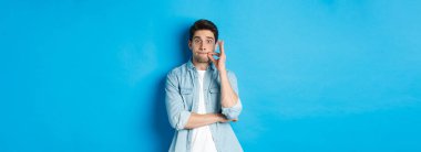 Ağzı sıkı yetişkin bir adam, söz ver sır tut, dudaklarını mühürle ve mavi arka planda dur..