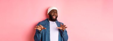 Tiksindirici, seçici siyah adam imajı rahatsız edici, kötü teklifi reddeden, nefret ve nefretle yüzünü buruşturan, pembe arka planda duran.