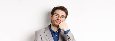 Gözlüklü komik ofis çalışanı, somurtuyor, nefes alıyor, kameraya bakıyor, beyaz arka plan.