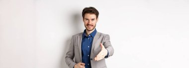 Kendine güvenen iş adamı elini uzatıp iş tokalaşması ve gülümseme için beyaz arka planda kendini tanıtır..