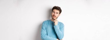 Yakışıklı genç bir adamın seçim yapması, düşünmesi, düşünmesi, bakması, beyaz arka planda durması..