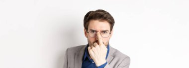 Takım elbiseli ciddi bir patron kaşlarını çatmış, gözlük takmış ve kamera karşısında şüpheli görünüyor..