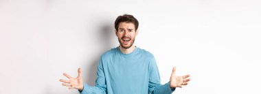 Hayal kırıklığına uğramış ve endişeli genç bir adamın el sıkışması, bir şeyleri açıklamaya çalışması, beyaz arka plana karşı endişeli durması..