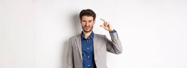 Hayal kırıklığına uğramış işadamı, küçük boyutlarda ve buruşuk suratlı üzgün, az gelirli, beyaz arka planda hoşnutsuz duruyor..