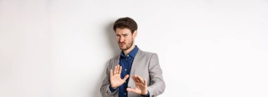 Uzak dur benden. İsteksiz işadamı endişeli bir yüz ifadesiyle geri adım atar, kötü teklifi engellemek için ellerini kaldırır, korkunç bir şeyi reddeder, hayır der ve teklifi reddeder, beyaz arka plan.