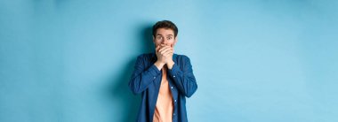 Şok olmuş, ağzı kapalı ve nefes nefese kalmış bir adam pusuya düşürülmüş. Mavi arka planda duran korkunç bir şeye tanık olmuş..