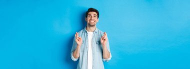 Şanslı adam dua ediyor ve dua ediyor. Dua eden yüzüyle mavi arka planda duruyor..