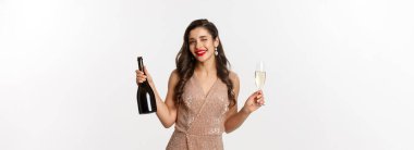 Kış bayramı kutlaması. Güzel bir kadın Noel ve yeni yıl partisinden zevk alıyor. Şampanya içiyor ve kameraya göz kırpıyor. Şık bir elbise içinde duruyor..