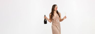 Noel partisi ve kutlama konsepti. Kırmızı dudaklı, lüks elbiseli, elinde bir bardak şampanya ve şişe olan zarif bir kadın..