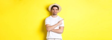 Turizm ve yaşam tarzı kavramı. Şüpheci adam şikayet ediyor, kötü bir şeyi işaret ediyor, hoşnutsuz görünüyor, sarı arka plan.