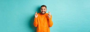 Endişeli bir adam dilek diliyor, bir şeyler umuyor, şans diliyor, turkuaz arka planda gergin duruyor..