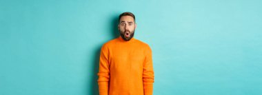 Şok olmuş ve kafası karışmış bir adam, tanıtım teklifine hayranlıkla bakıyor, turkuaz arka planda fotokopi alanının yanında duruyor..