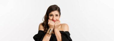 Moda ve güzellik konsepti. Endişeli görünen, tırnaklarını yiyen ve beyaz arka planda duran gergin bir kadın..