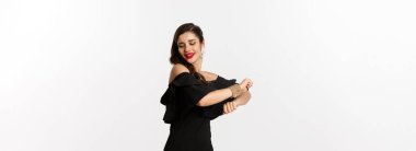 Moda ve güzellik. Çekici kadın mutlu hissediyor ve siyah parti elbisesi içinde dans ediyor, beyaz arka plana karşı kaygısız duruyor..