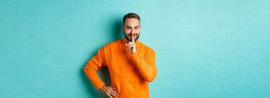 Mutlu adam sesini alçalt, sus ve gülümse, sürprize hazırlan, kameraya sus, turkuaz arka planda dur..