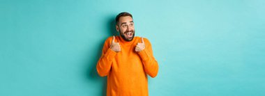 Neşeli adam övgüler yağdırıyor ve sol üst köşeye bakıyor, afallamış, süper havalı ürünler sergiliyor, açık mavi arka planda duruyor..