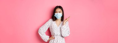 Covid-19, karantina ve yaşam tarzı konsepti. Güzel ve kendine güvenen Asyalı kadın. Elbise ve yüz maskesi takmış. Kendinden emin görünüyor..