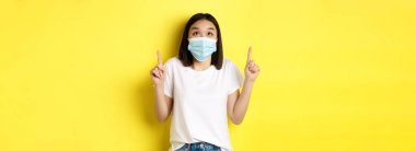 Covid-19, salgın hastalık ve sosyalleşme konsepti. Beyaz tişörtlü ve Coronavirüs 'ten gelen tıbbi maskeli genç Asyalı kadın özel bir teklif sunuyor..