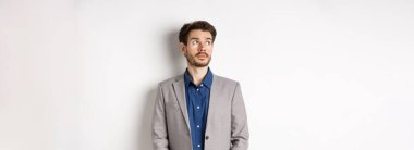 Takım elbiseli düşünceli üzgün işadamı sol üst köşedeki logoya bakıyor, düşünüyor veya uzaklaşıyor, beyaz arka planda duruyor..