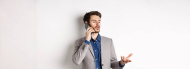 Yakışıklı işadamının telefonda iş görüşmesi cep telefonuyla konuşurken el kol hareketi yapması, sohbet etmesi, beyaz arka plan..